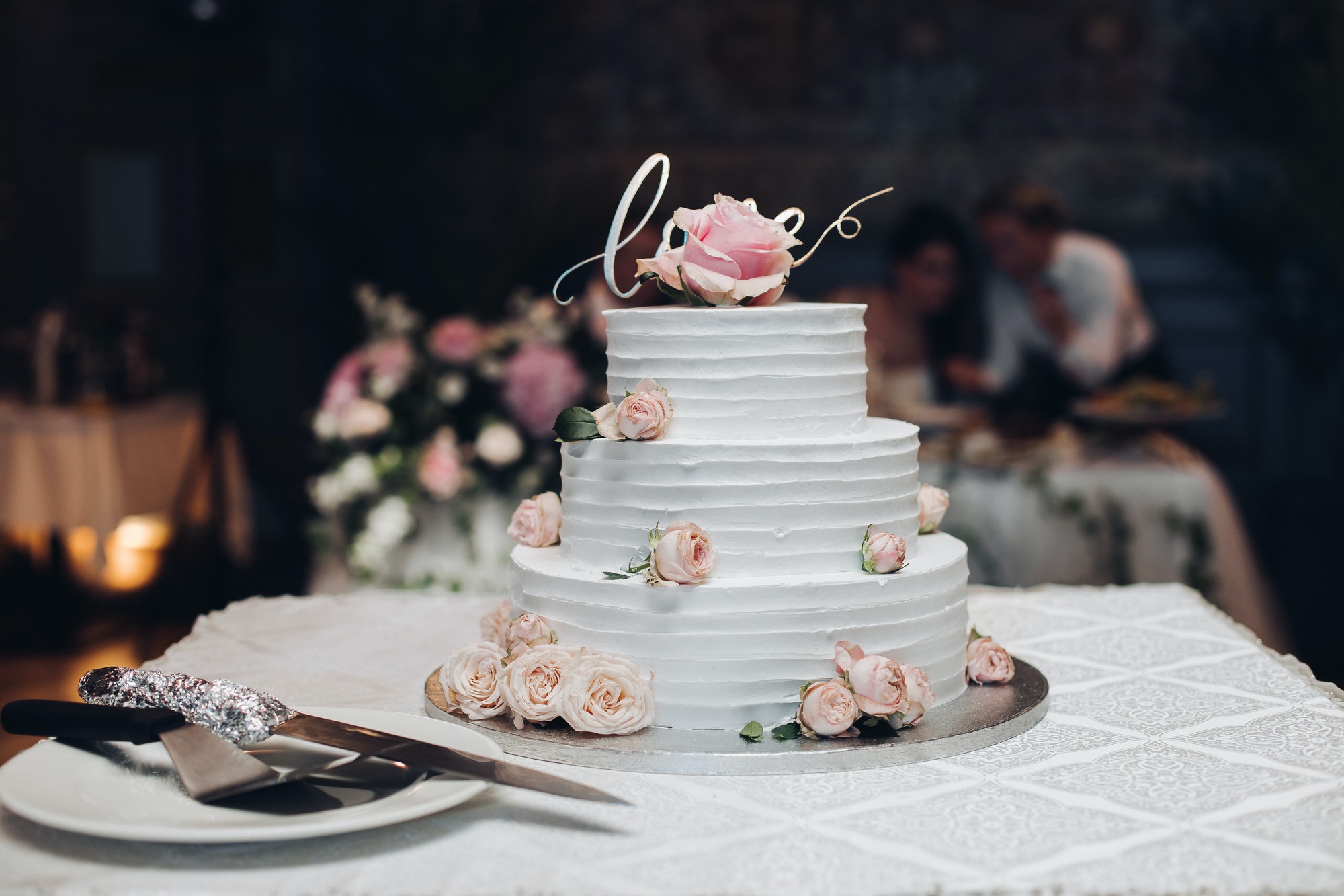 Beautiful wedding cake with flowers on table